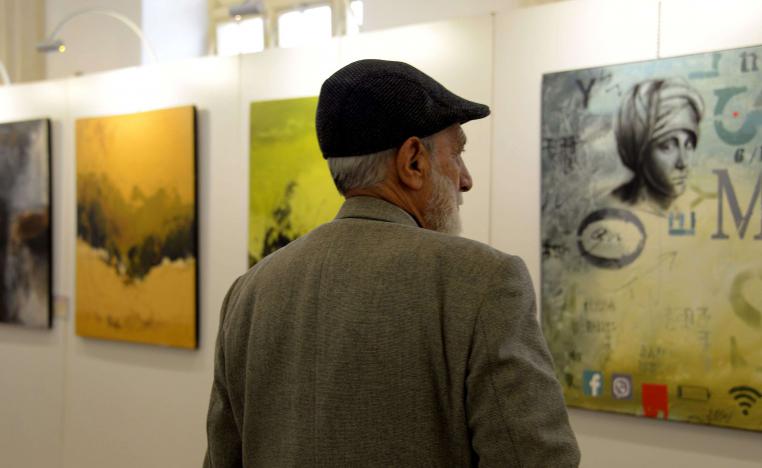 زائر يحدق في لوحات أول معرض فني يقام في الموصل في يناير 2019، بعد دحر الجهاديين