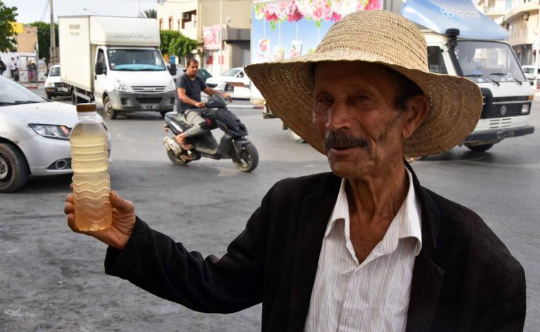 A street vendor holds a bottle of legmi, a coveted date palm drink, in the southwestern Tunisian town of Gabes