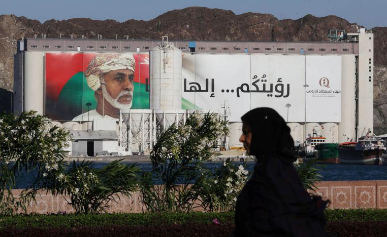 عمانية تمر بالقرب من لوحة تغطي مبنى حكومي في مسقط