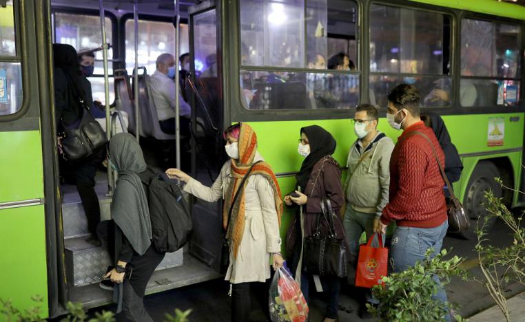 إيرانيون يرتدون أقنعة واقية أثناء ركوبهم حافلة