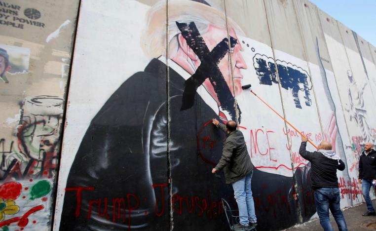 فلسطيني يشطب صورة جدارية للرئيس السابق دونالد ترامب من سور عازل بين إسرائيل والضفة الغربية