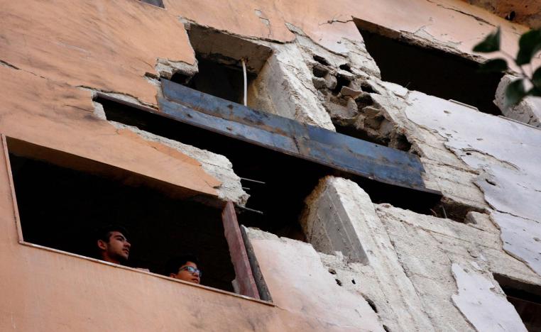 سوريون ينظرون على اثار قصف على منازلهم في دمشق
