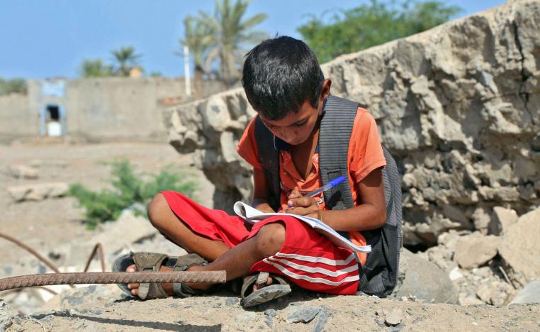 طفل يمني يقرأ عند أطلال مدرسته المدمرة في الحديدة غرب اليمن