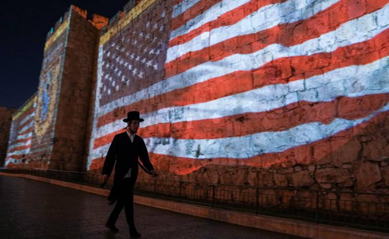 إسرائيلي يمر بجانب علم أميركي في القدس