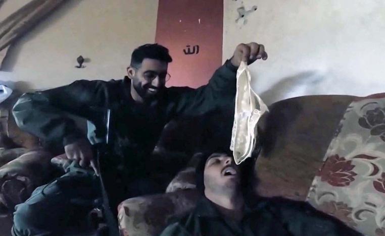 An Israeli soldier dangling white satin underwear over the open mouth of a comrade lying on a sofa