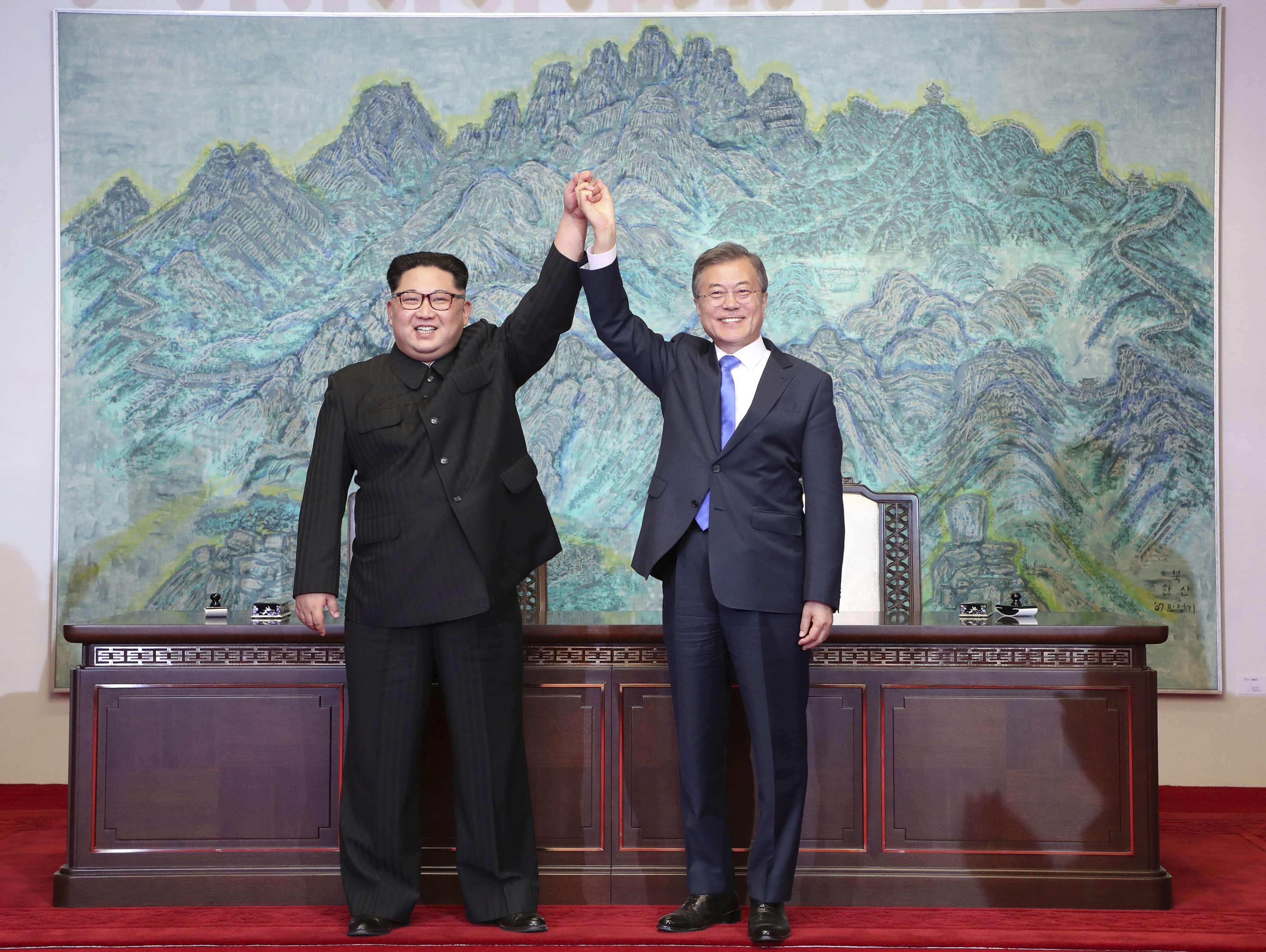 الرئيس الكوري الشمالي يمسك يد رئيس حكومة كوريا الجنوبية