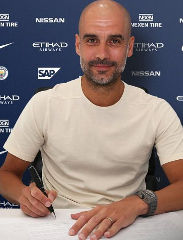 جوسيب غوارديولا يمسك قلما اثناء توقيع عقد جديد