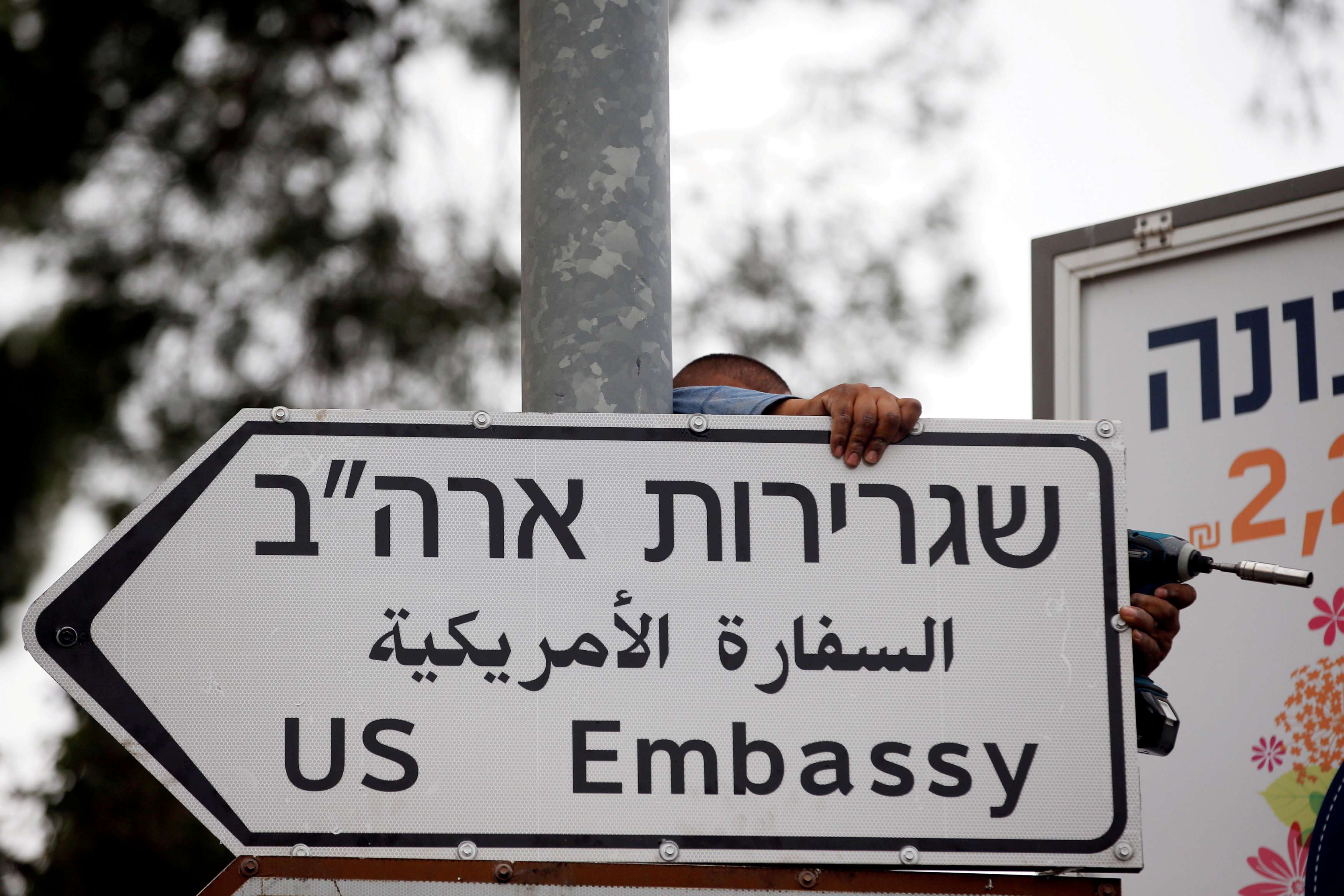 تعليق لافتة مرورية في القدس تشير إلى موقع السفارة الأميركية