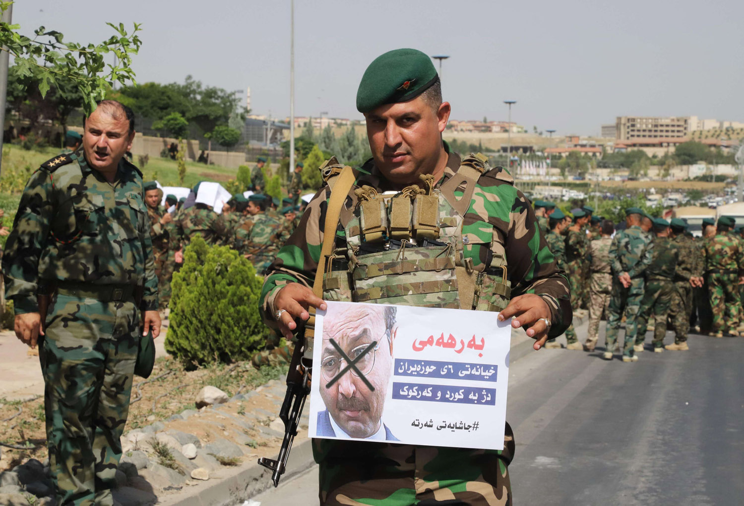 مقاتل من البيشمركه يحمل ملصقا يهاجم فيه رئيس وزراء كردستان السابق برهم صالح