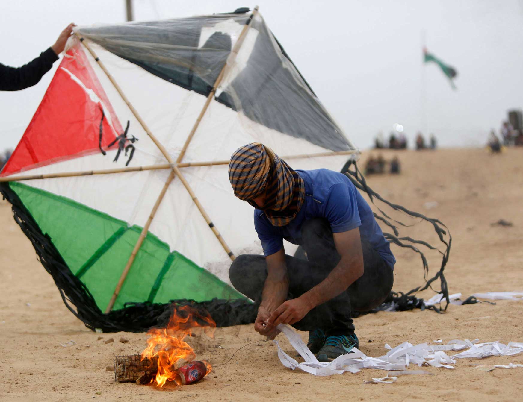 فلسطيني يجهز طائرة مشتعلة قبل قبل محاولة ارسالها الى ما بعد السياج الحدودي مع إسرائيل