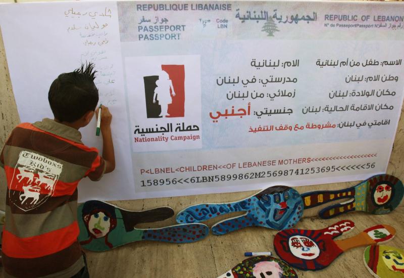 A child writes his name on a banner during a demonstration for the right to Lebanese nationality in Beirut