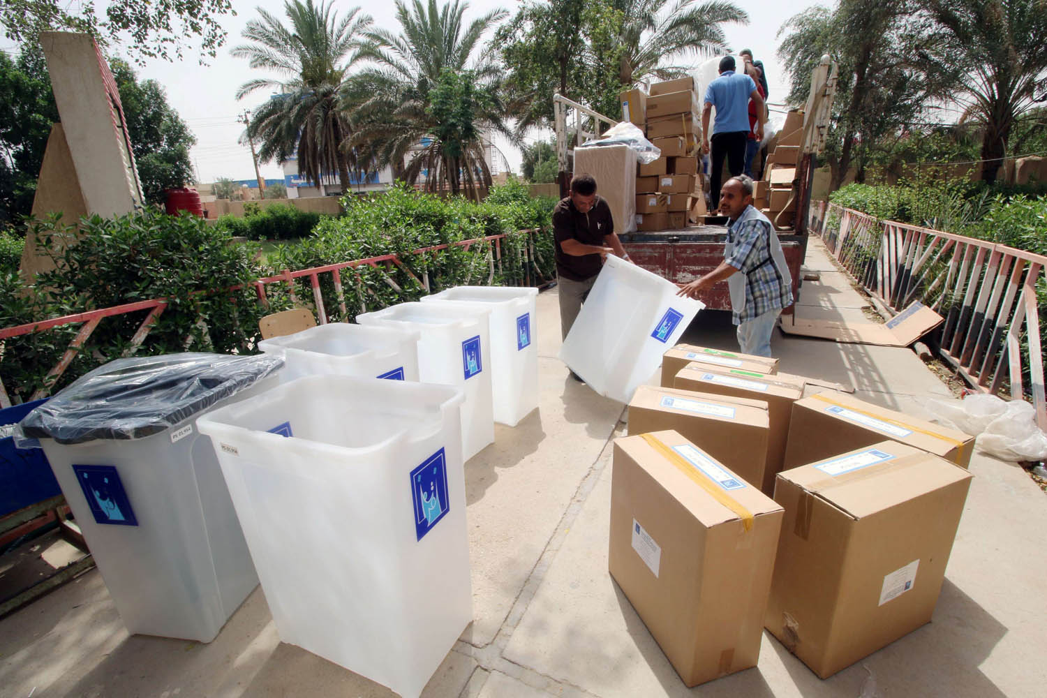 عمال عراقيون يحملون صناديق انتخابية في البصرة