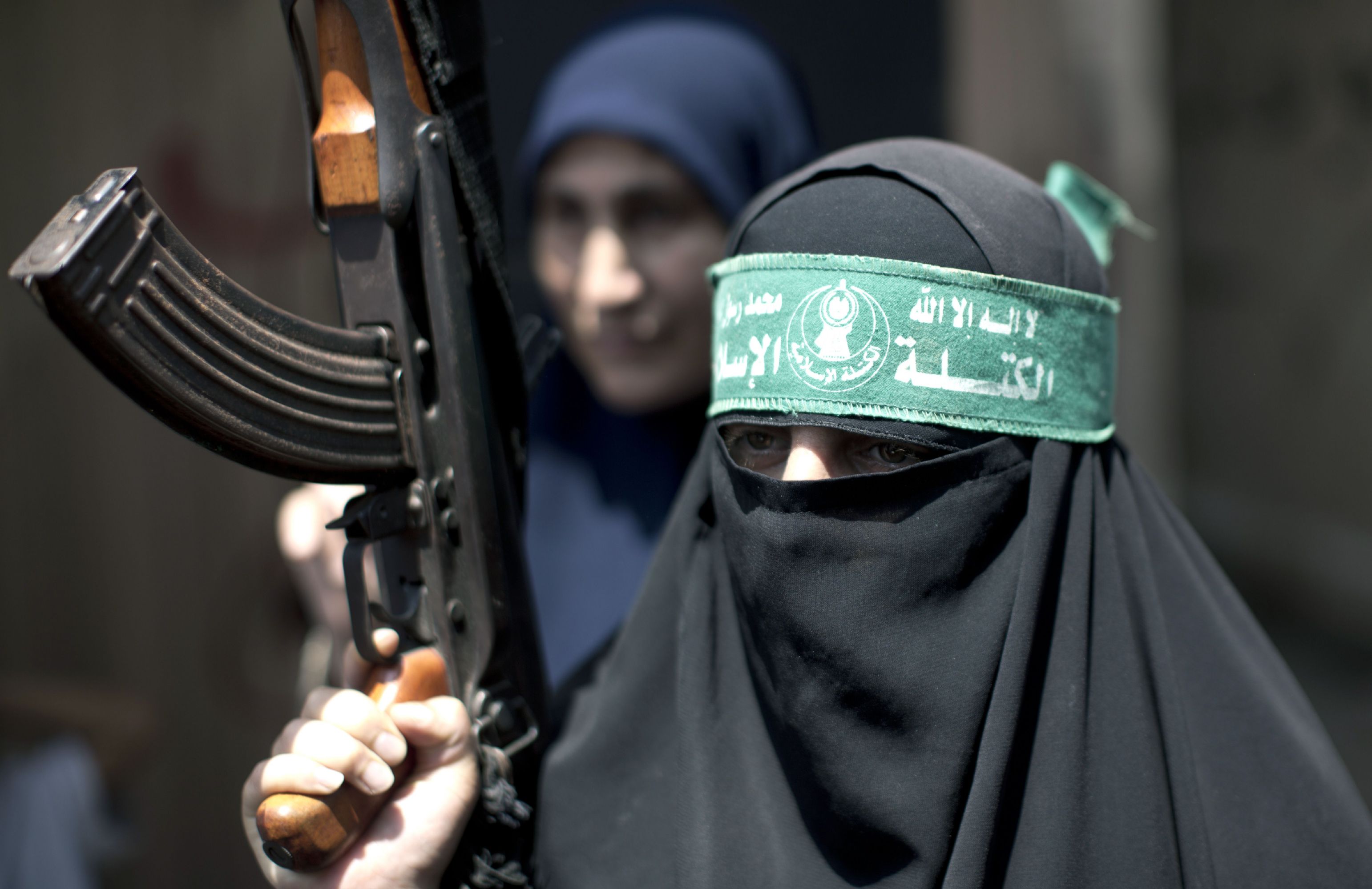 Palestinian woman Hamas supporter holds up a rifle.