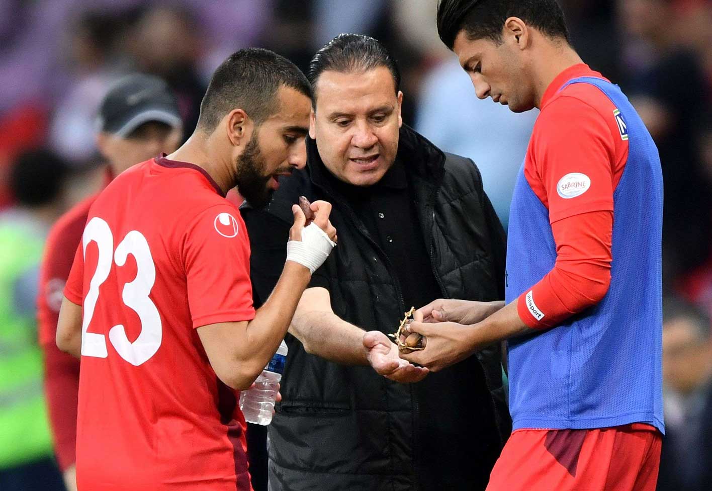 المدير الفني التونسي نبيل معلول (يمين) يوزع التمور على اللاعبين