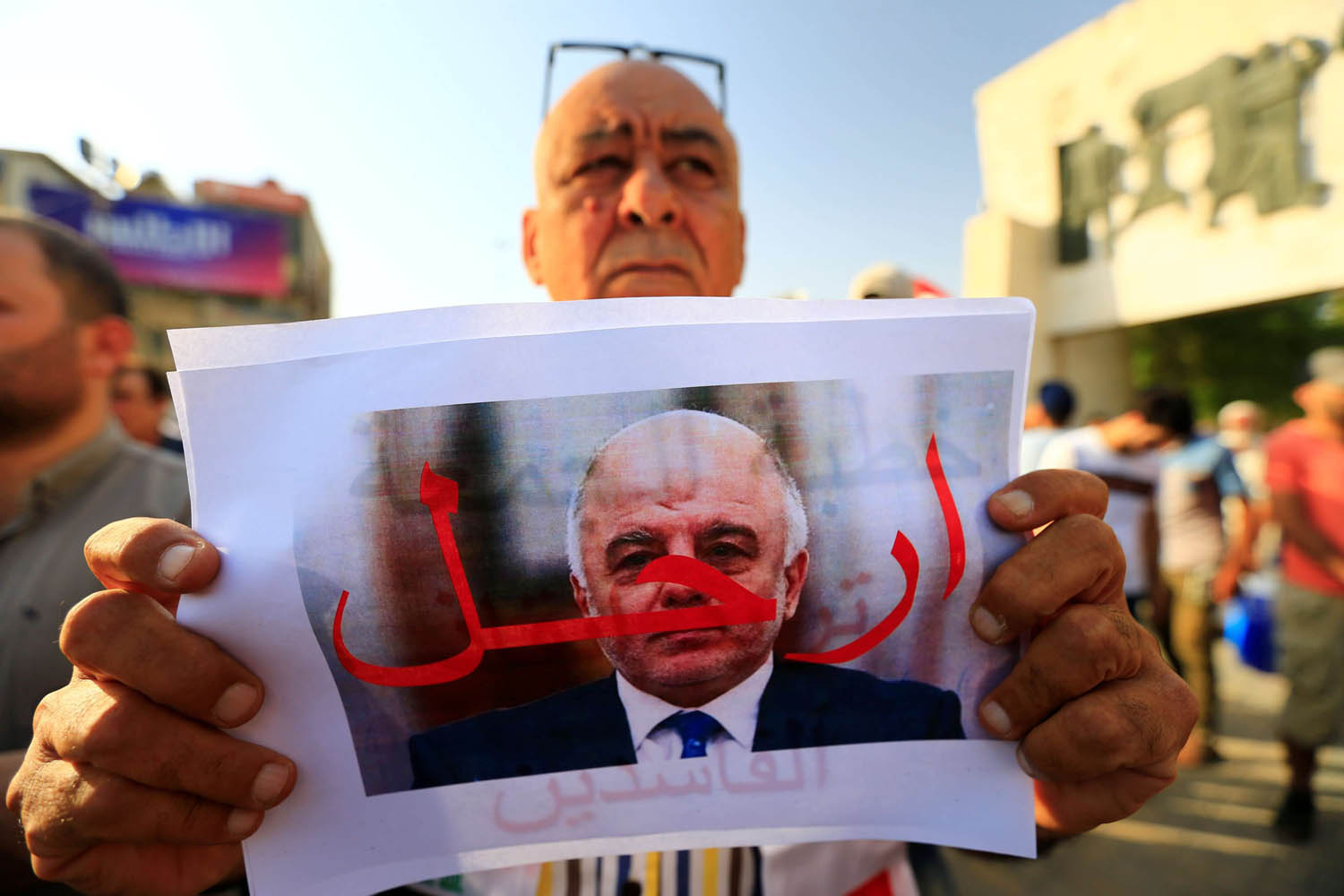متظاهر عراقي يحمل صورة للعبادي تطالبه بالرحيل