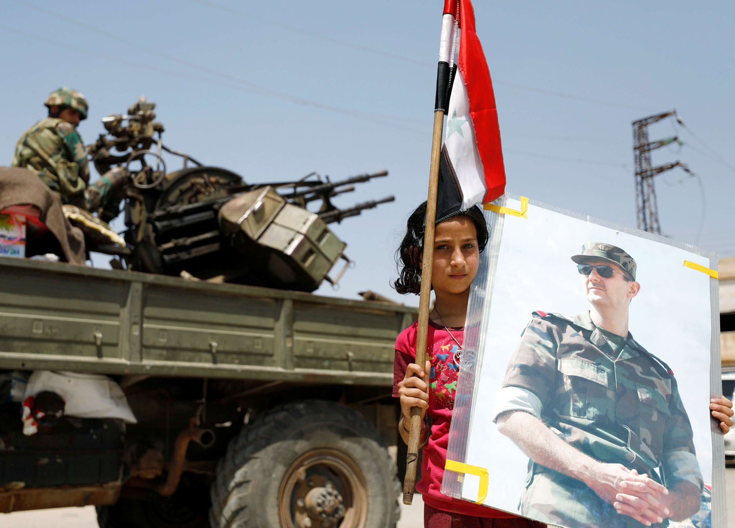 طفلة سورية ترفع صورة للأسد على خلفية مدفع مقاوم للطائرات