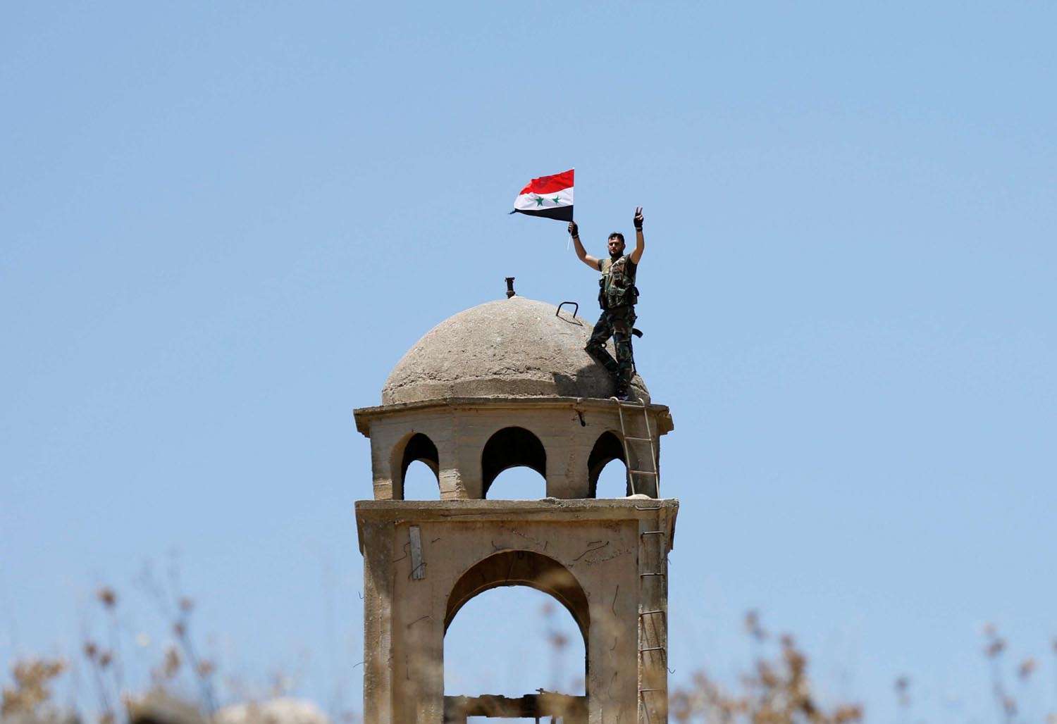 جندي سوري يرفع علم بلاده على كنيسة في مدينة القنيطرة