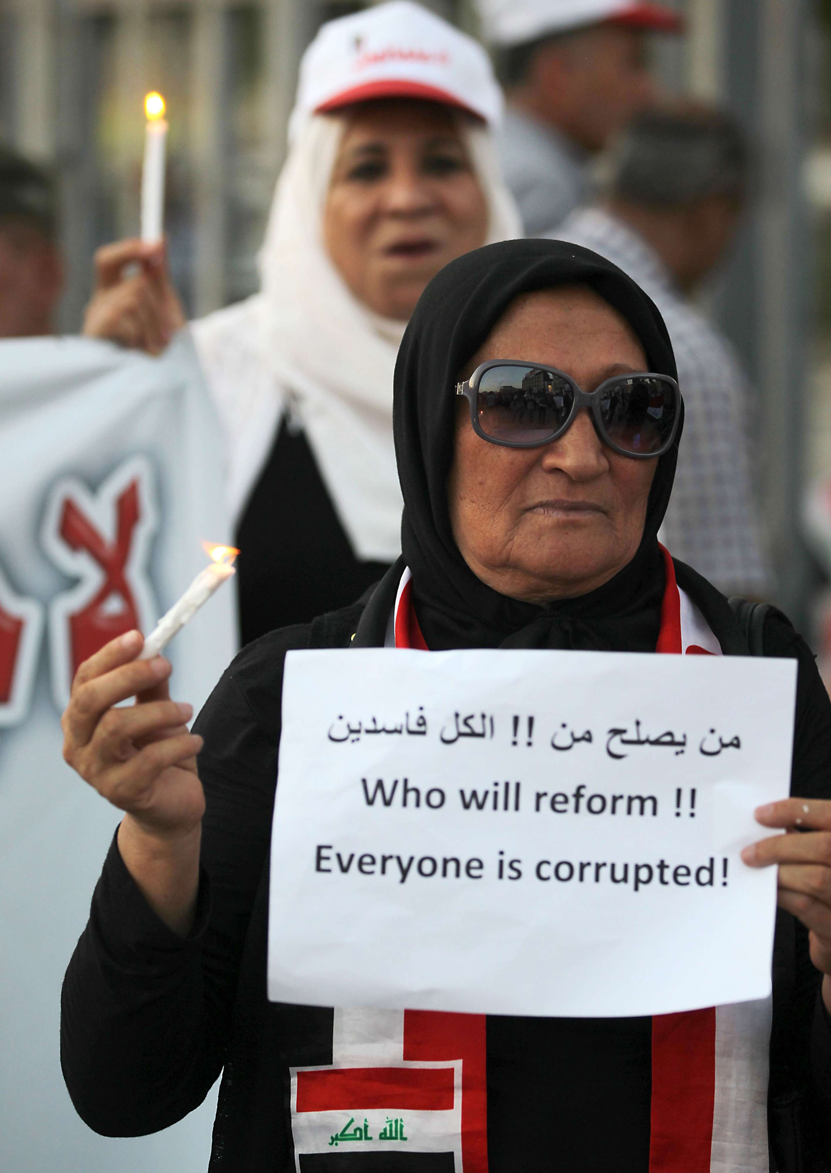 عراقية تحمل لافتة تتهم كل السياسيين بالفساد
