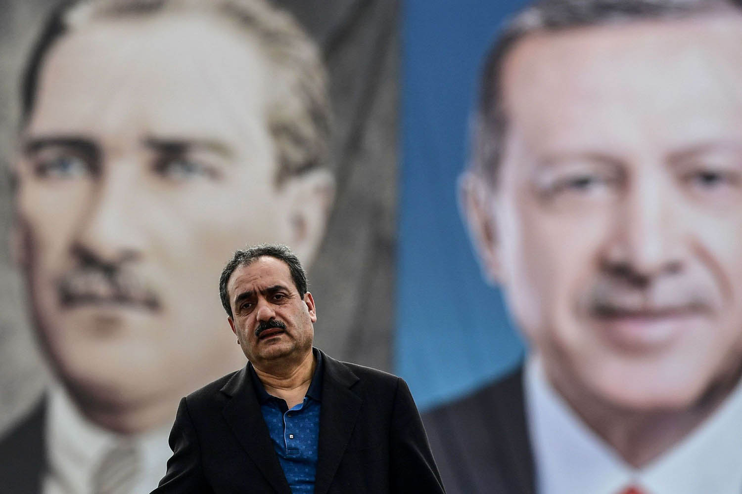 تركي يقف على خلفية صورتين لأردوغان وأتاتورك