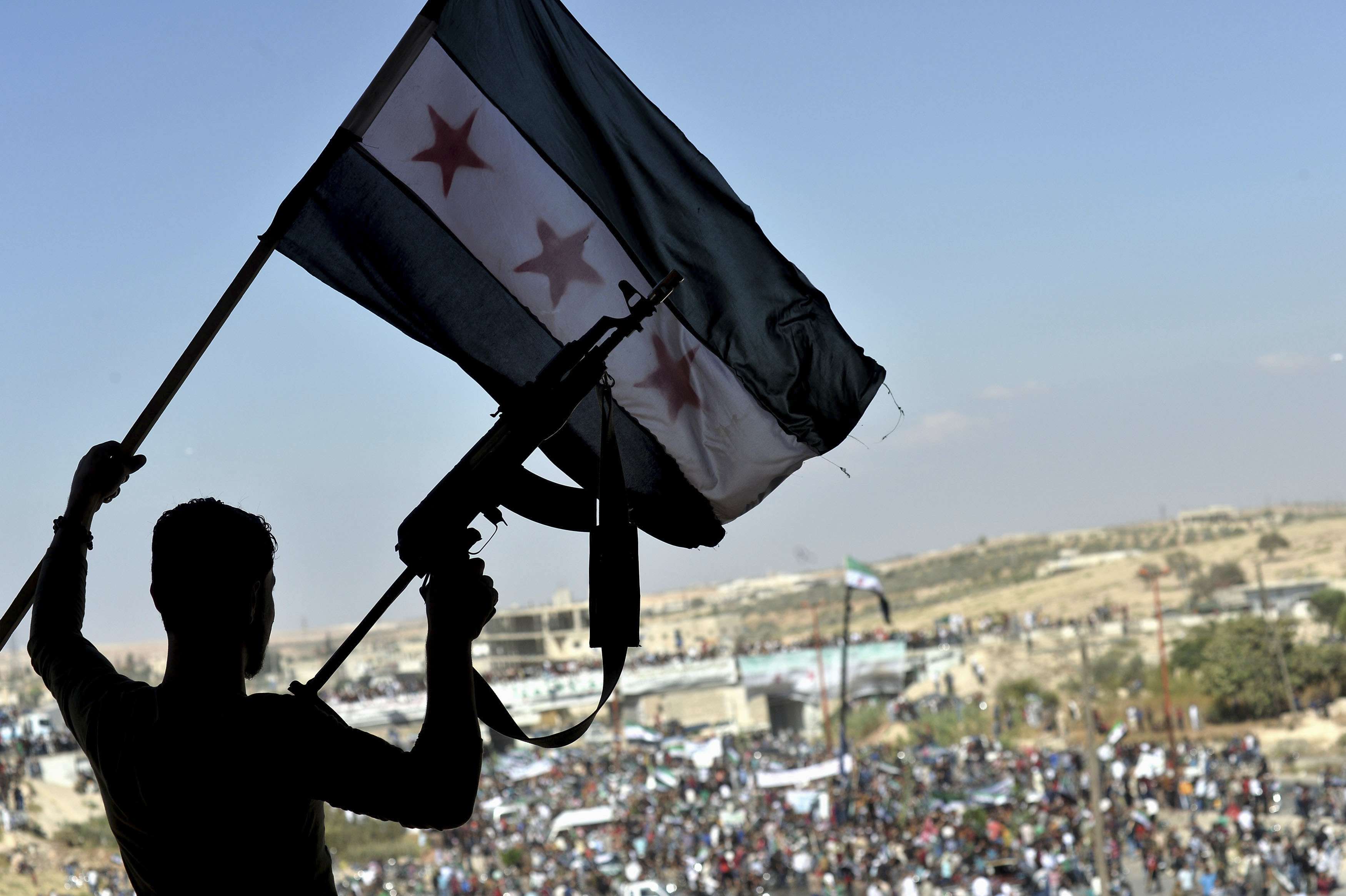 مقاتل من فصائل المعاضة يحمل العلم السوري وسلاح