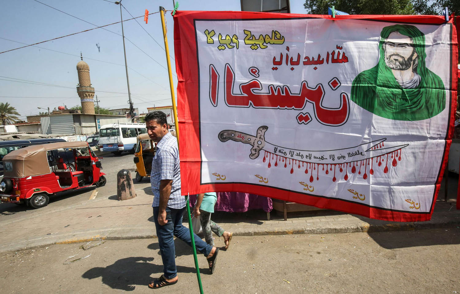 عراقي يمر بالقرب من لافتة طائفية في مدينة الصدر ببغداد