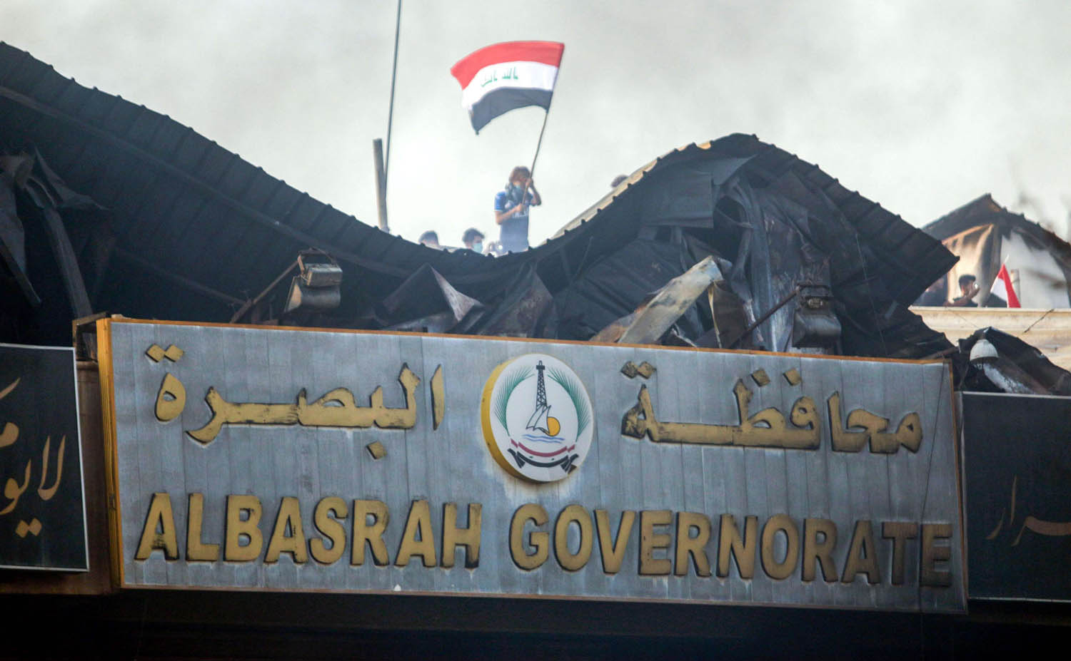 عراقيون على سطح مبنى محافظة البصرة بعد حرقه