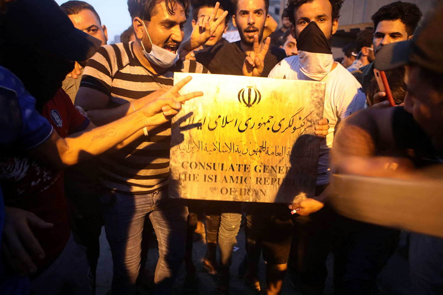 عراقيون يستعرضون لوحة مبنى القنصلية الإيرانية المحترقة في البصرة