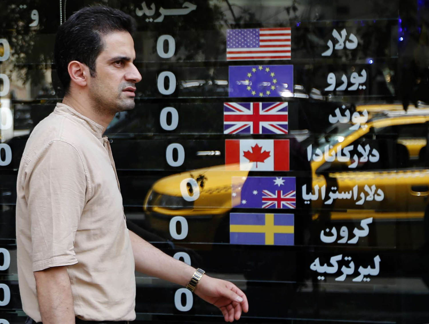 إيراني يمر بجانب محل صرافة في طهران