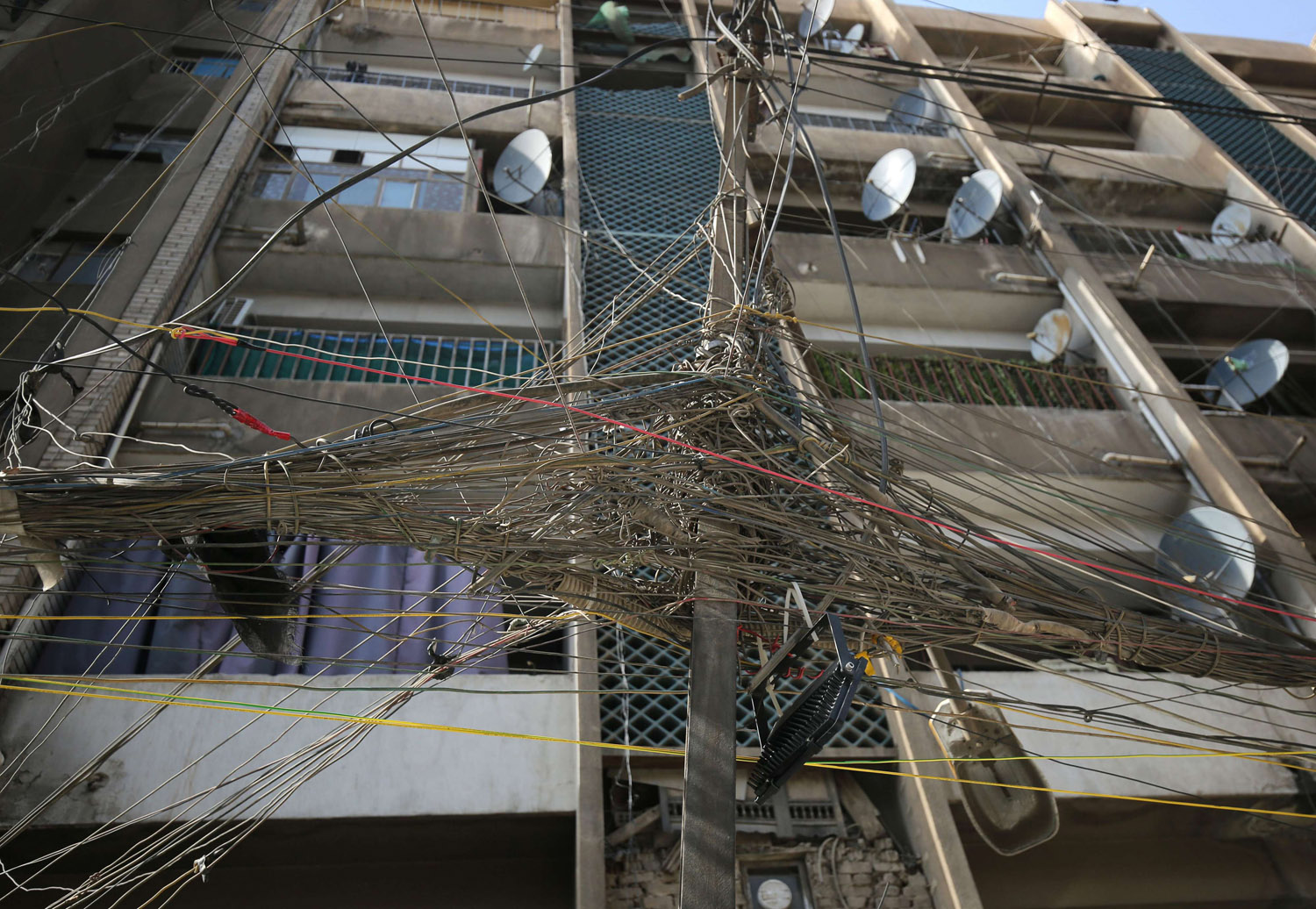 واجهة مبنى في بغداد تتشابك أمامها توصيلات الكهرباء من مولدات خاصة