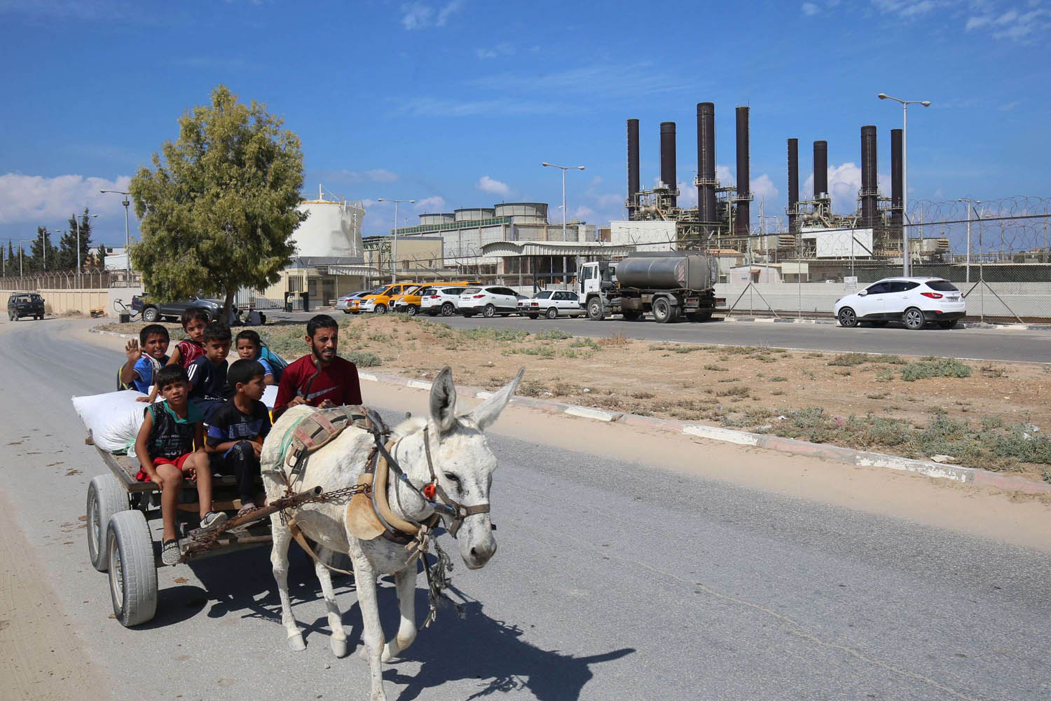 عربة يجرها حمار تمر أمام محطة توليد الوقود في غزة