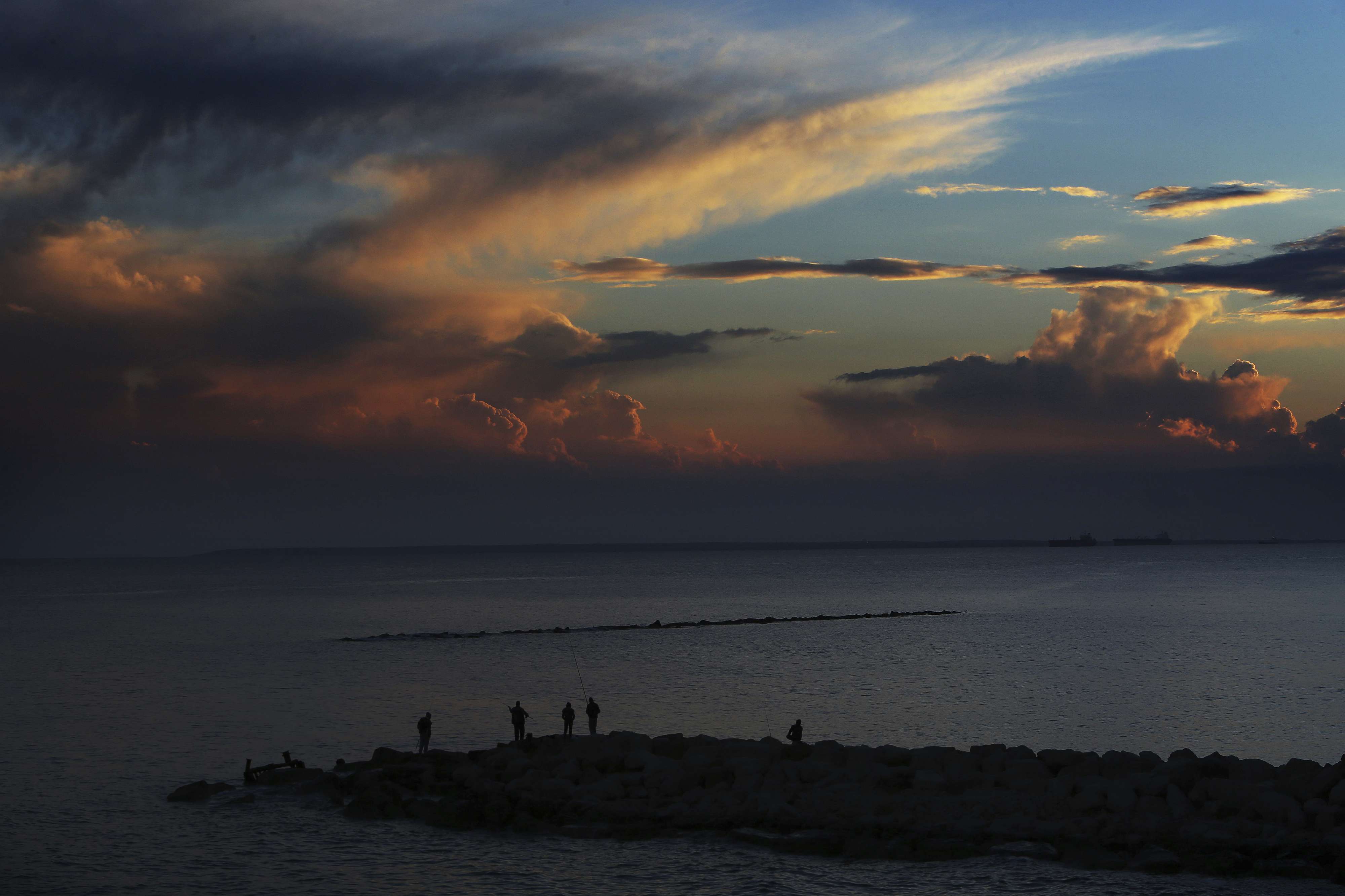 Men fishing with their fishing rods at the sea during a sunset in the southern port city of Limassol, Cyprus, Friday, Feb. 23, 2018.