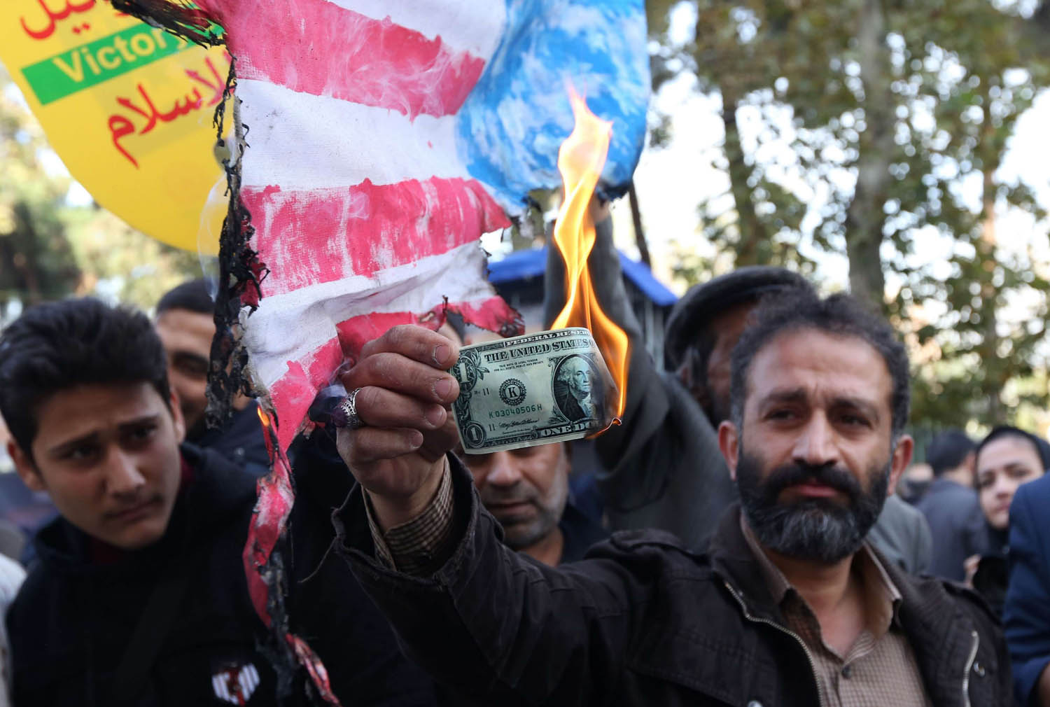 إيراني يحرق دولار أميركي في تظاهرة احتجاج على عودة العقوبات