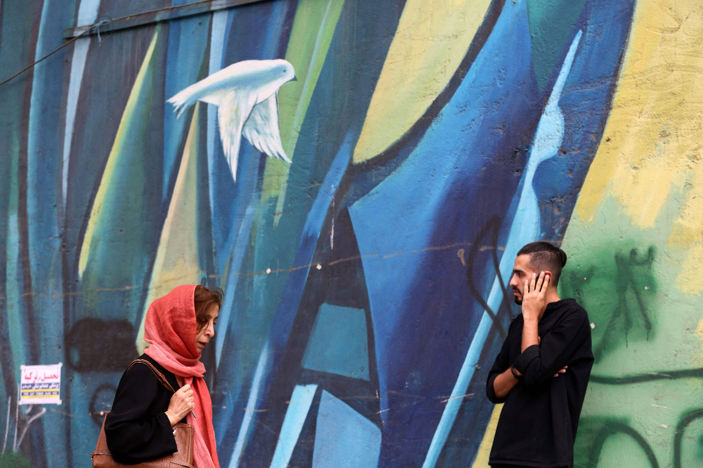 Iranians walk past colourful walls in the capital Tehran.