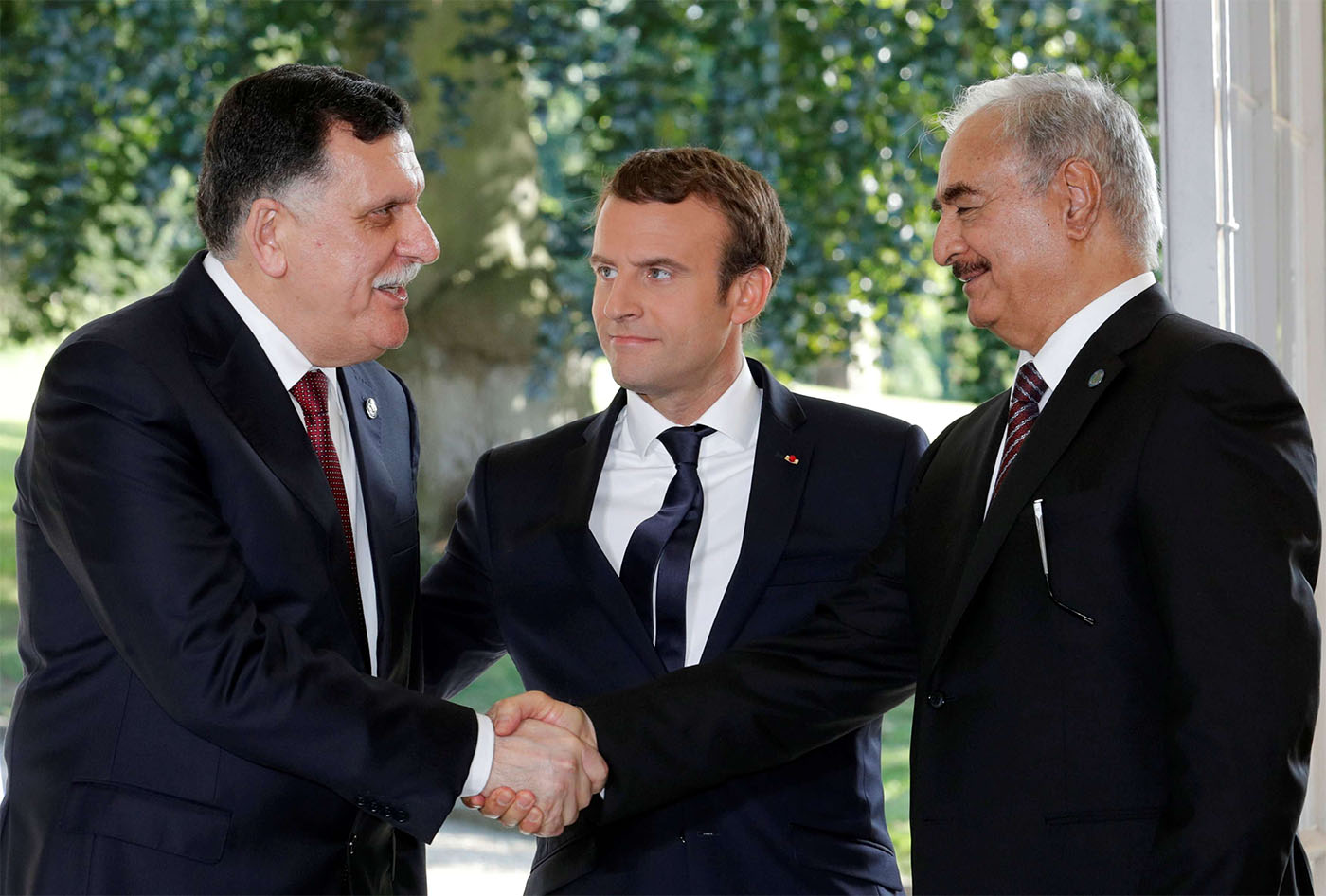 French President Emmanuel Macron stands between Libyan Prime Minister Fayez al-Sarraj (L), and General Khalifa Haftar (R), commander in the Libyan National Army (LNA)
