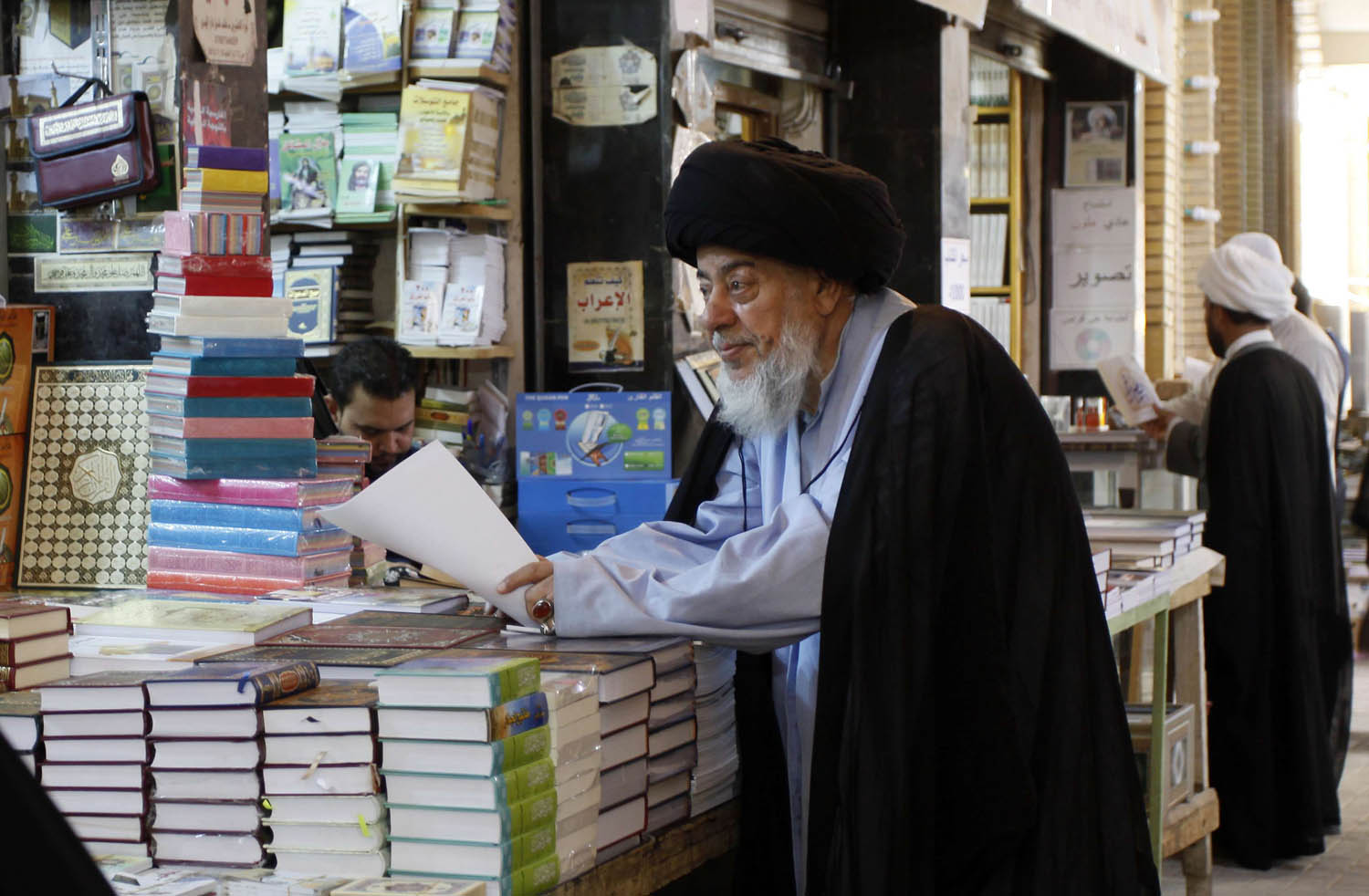رجل دين يقف عند مكتبة تبيع كتبا دينية في النجف