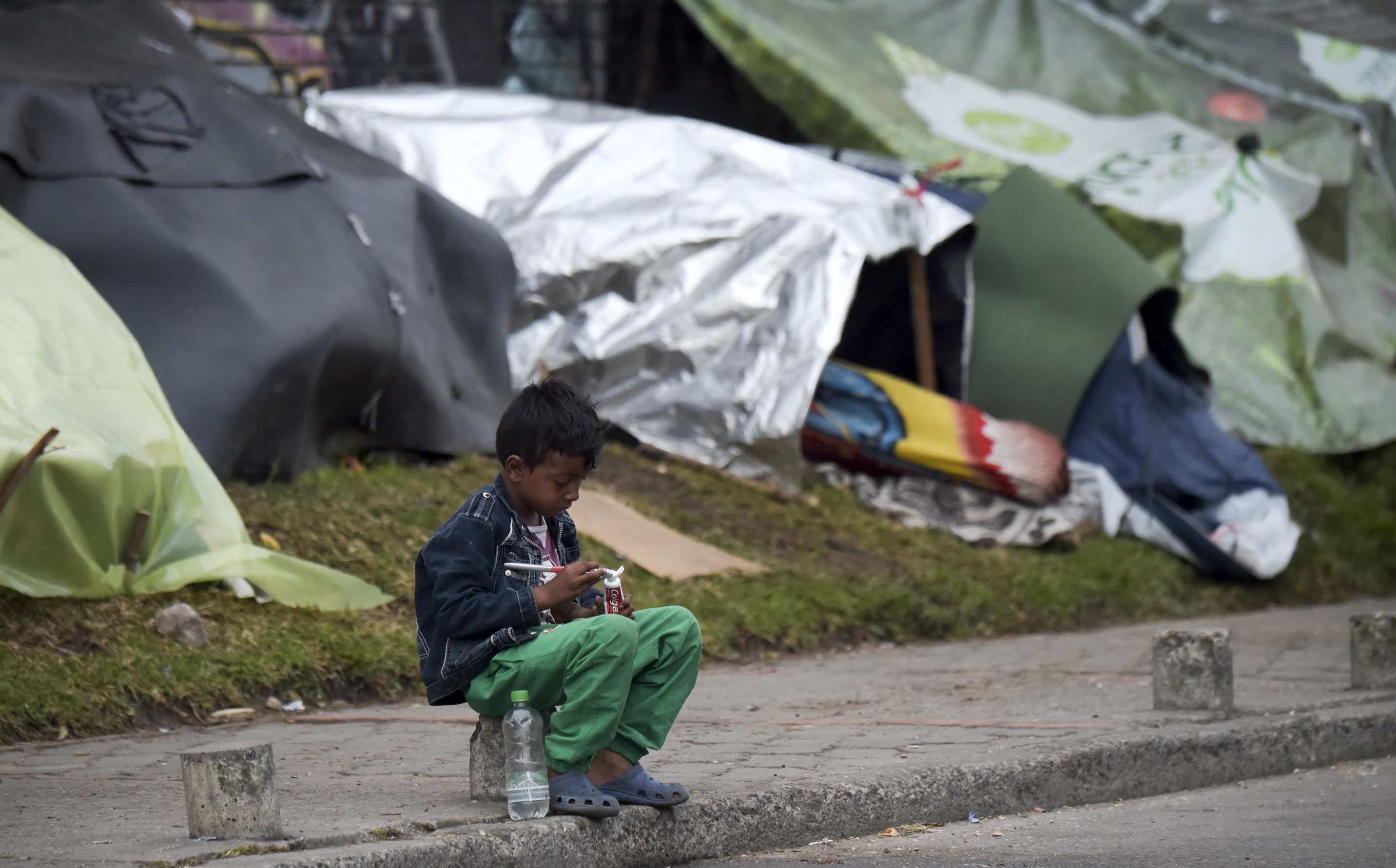 A Venezuelan migrant child prepares to brush his teeth at an improvised camp near a bus terminal in Bogota on November 9, 2018.
