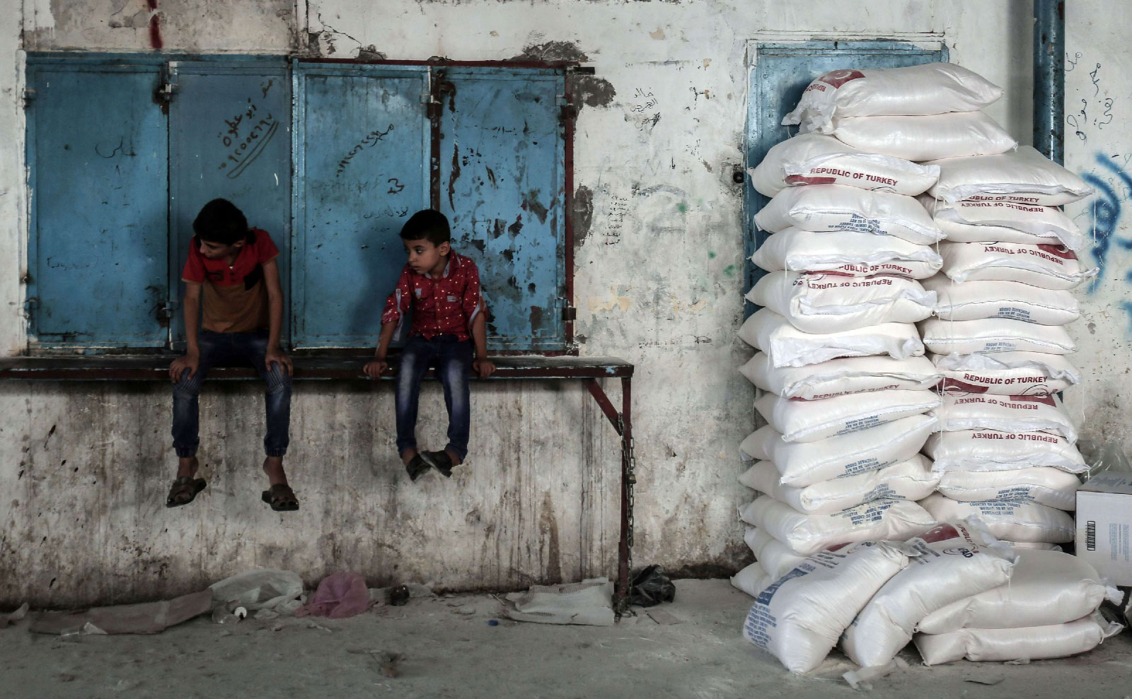 Palestinian children sit by sacks of food aid in the town of Rafah, southern Gaza Strip.
