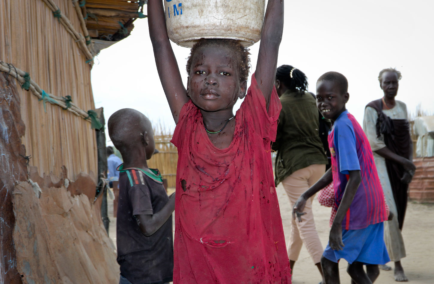 A young girl carries water on her head in Koythiey displaced person's camp on the outskirts of Bentiu town in South Sudan.
