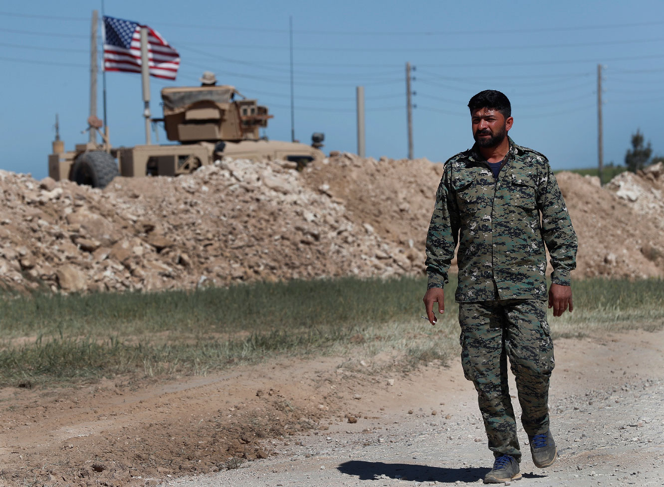 A US-backed Syrian Manbij Military Council soldier passes a US position near the tense front line with Turkish-backed fighters, in Manbij, north Syria.