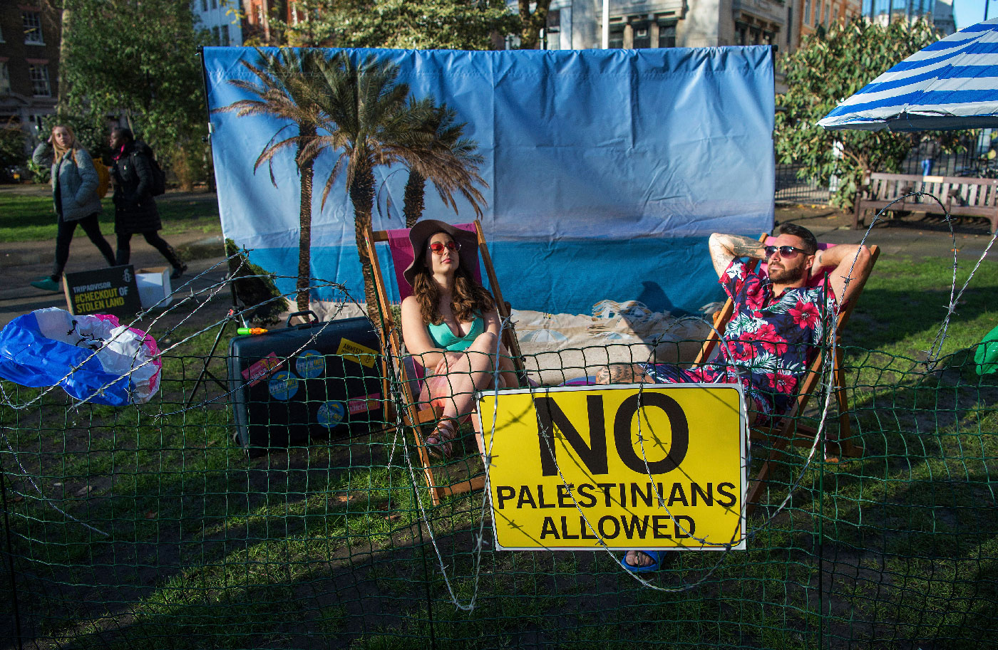 Two models sit on a "barbed-wire beach" outside the offices of TripAdvisor in Soho Square, as part of an Amnesty International campaign calling on the firm and other travel companies to stop listing rooms and activities in Israeli settlements in the Palestinian Territories on 30 January 2019 in London, England.