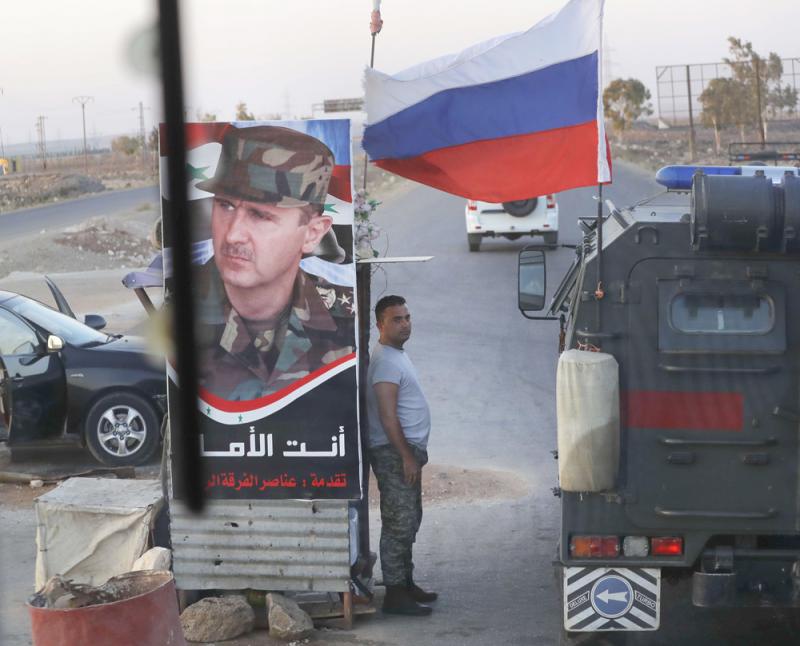 A shift in direction. A Syrian soldier stands at a checkpoint as a Russian military police vehicle passes by near the village of Almajdiyeh, last August.