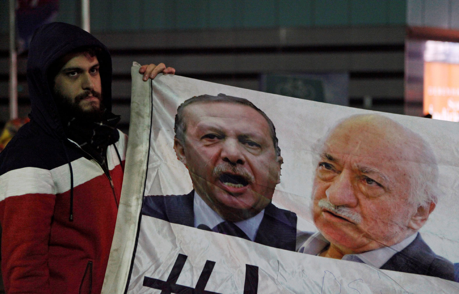 A demonstrator hold pictures of Turkey's Prime Minister Tayyip Erdogan and Turkish cleric Fethullah Gulen.