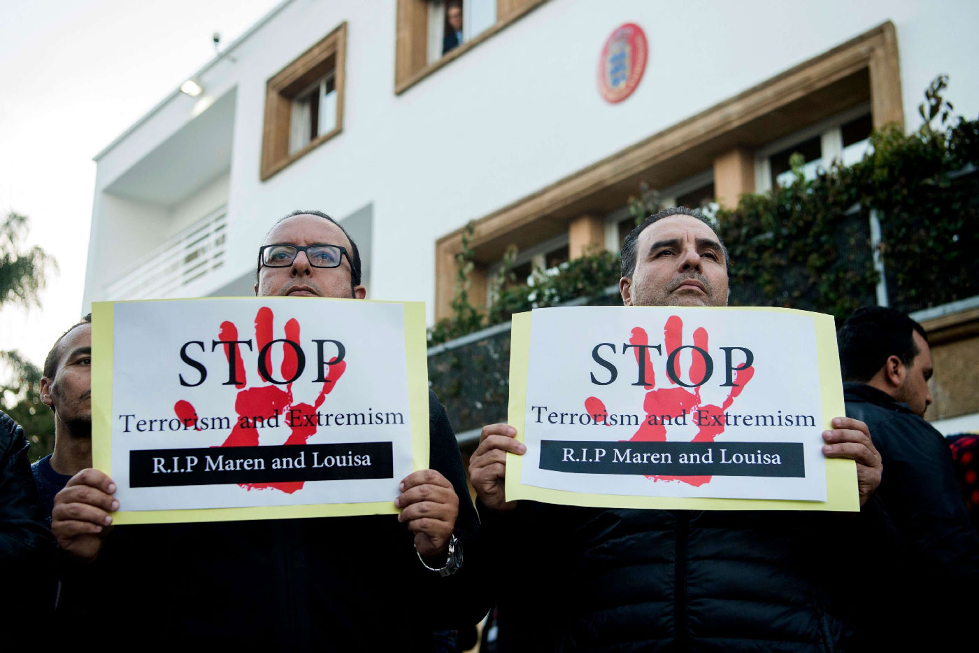 Moroccans holds placards as people pay tribute to murdered Danish Louisa Vesterager Jespersen and Norwegian Maren Ueland in Rabat, in front the Danish ambassy on December 22, 2018.