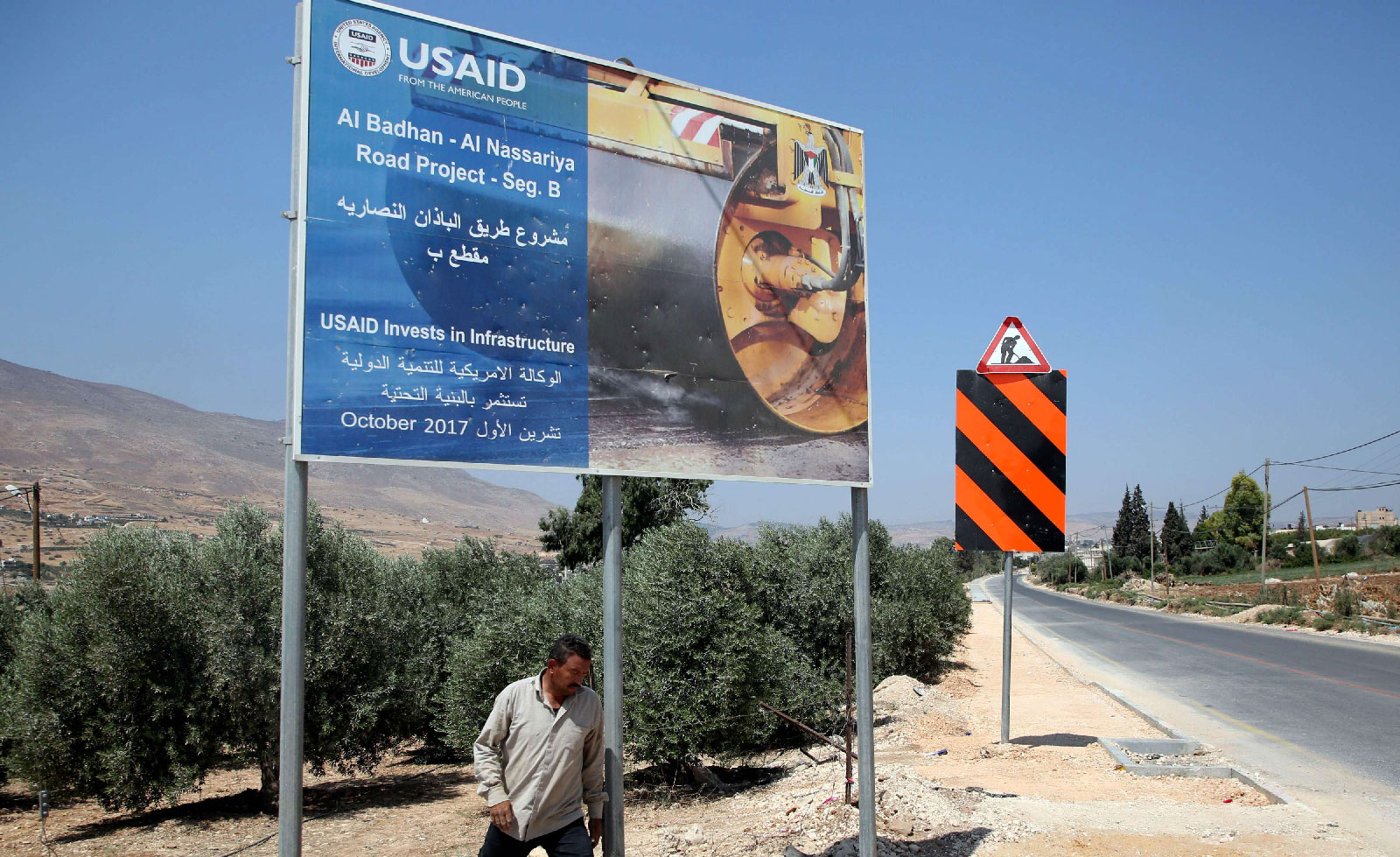 A Palestinian man walks near a USAID billboard in the village of al-Badhan, north of Nablus in the occupied West Bank on August 25, 2018.