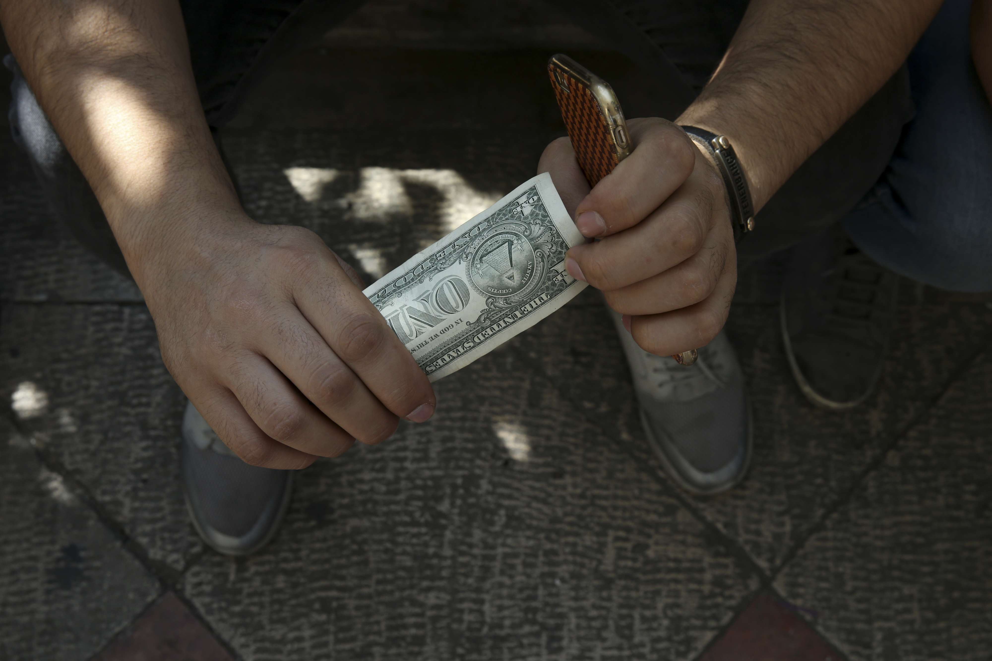 An Iranian street money exchanger holds a U.S. banknote in downtown Tehran, Iran, Tuesday, Oct. 2, 2018.
