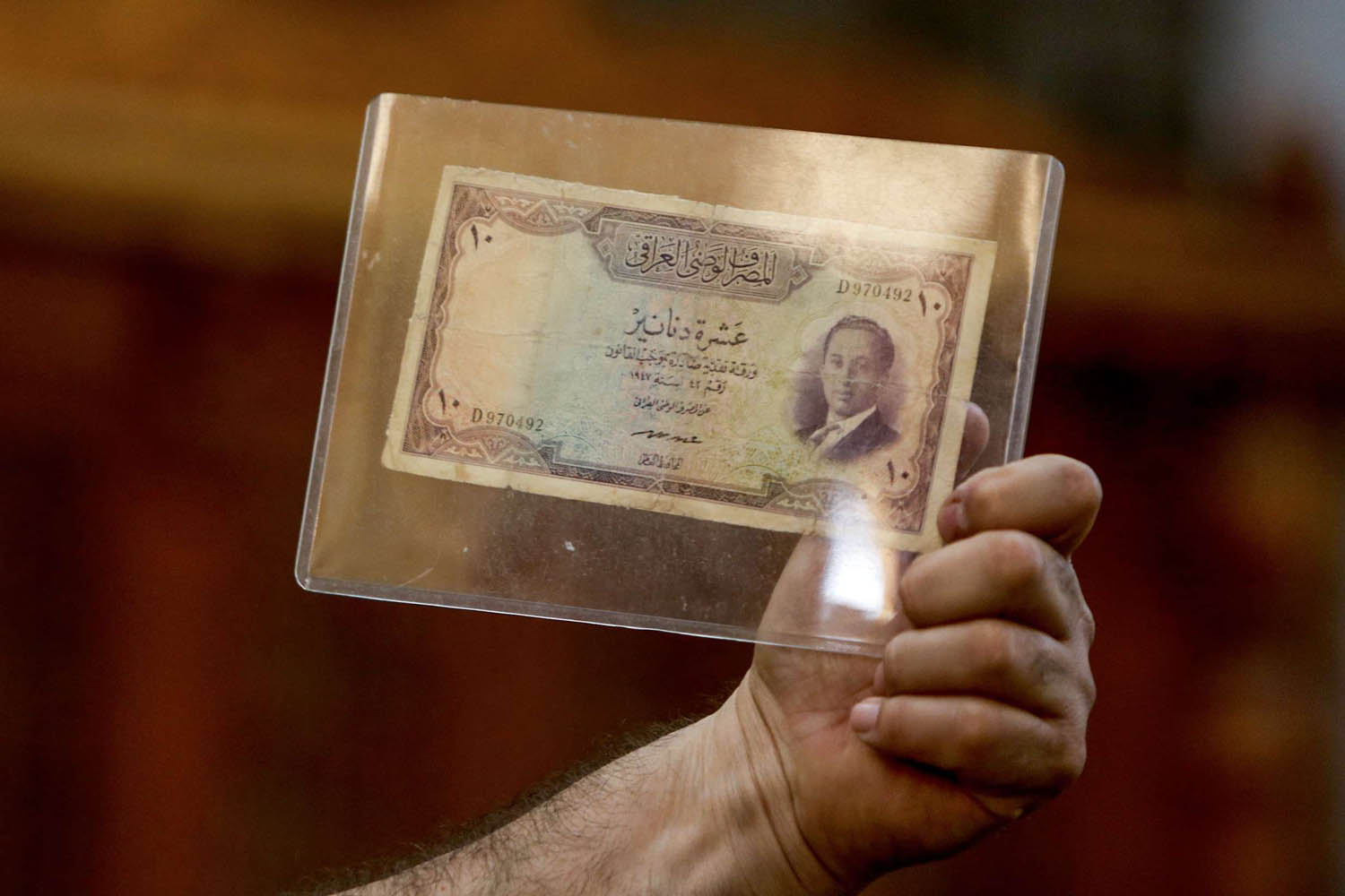 عراقي يرفع ورقة نقدية عليها صورة الملك فيصل الثاني في مزاد ببغداد