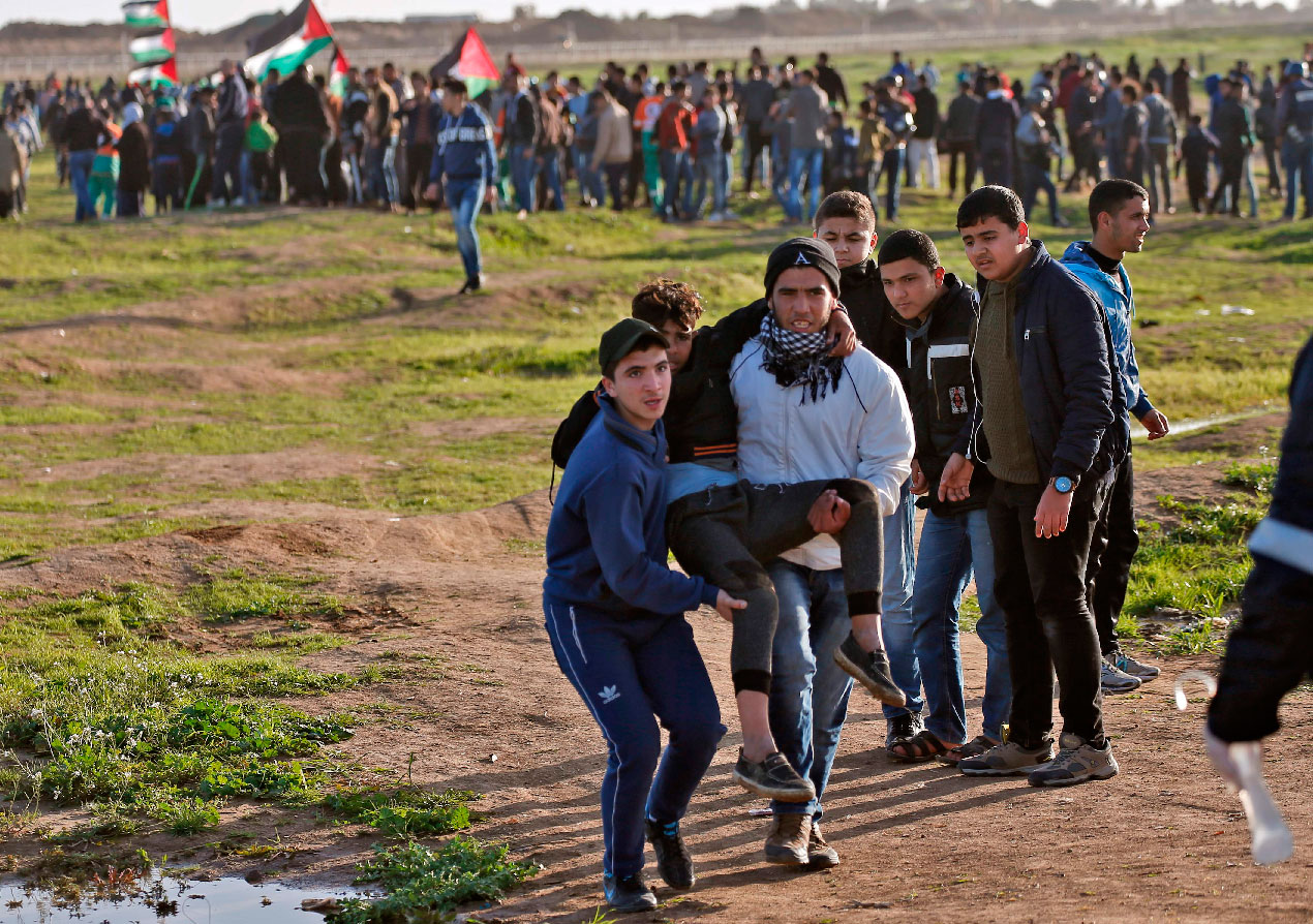 Palestinian demonstrators evacuate a wounded comrade during a demonstration near the fence east of Gaza City, on February 8, 2019.