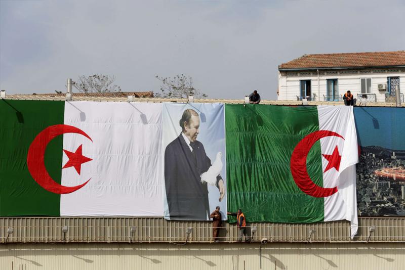 Algerian city employees install national flags and a poster of President Abdelaziz Bouteflika on a street in Algiers.