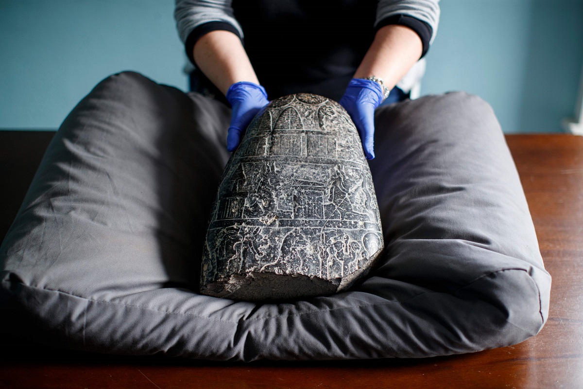 موظفة في المتحف البريطاني تمسك حجر كودورو البابلي