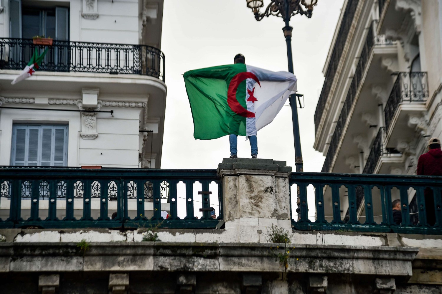 شاب جزائري يرفع علم بلاده على جسر في العاصمة
